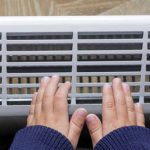 Mother and son heating up a hand in front of an electric heater